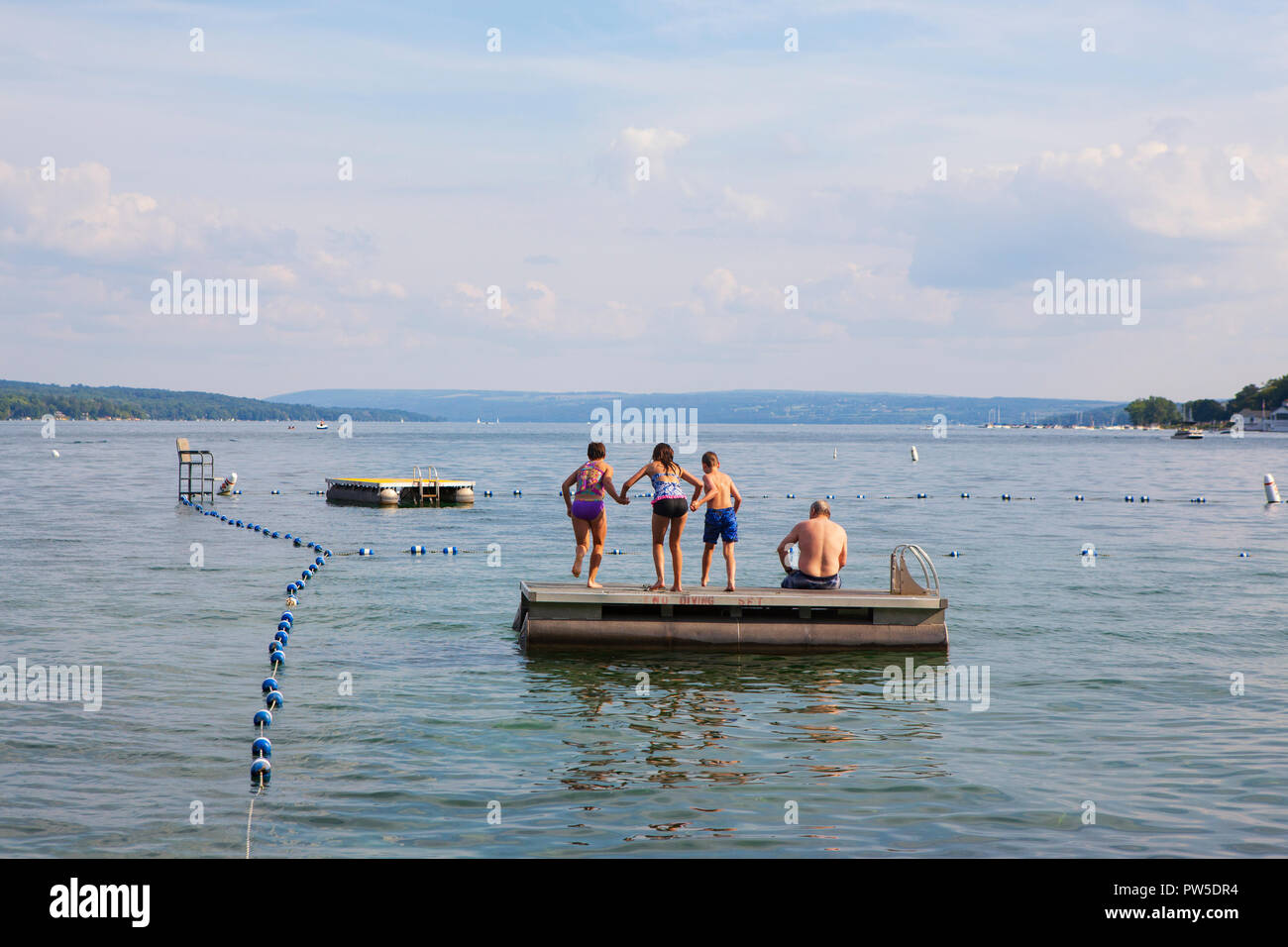 Una famiglia salti in Lago Skaneateles, Skaneateles, New York, Stati Uniti d'America, 14 giugno 2013. Foto Stock