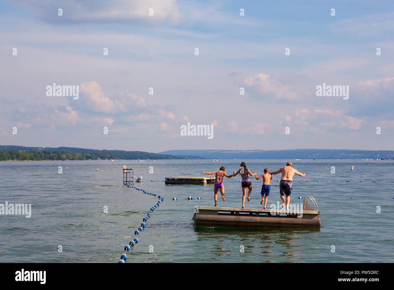 Una famiglia salti in Lago Skaneateles, Skaneateles, New York, Stati Uniti d'America, 14 giugno 2013. Foto Stock