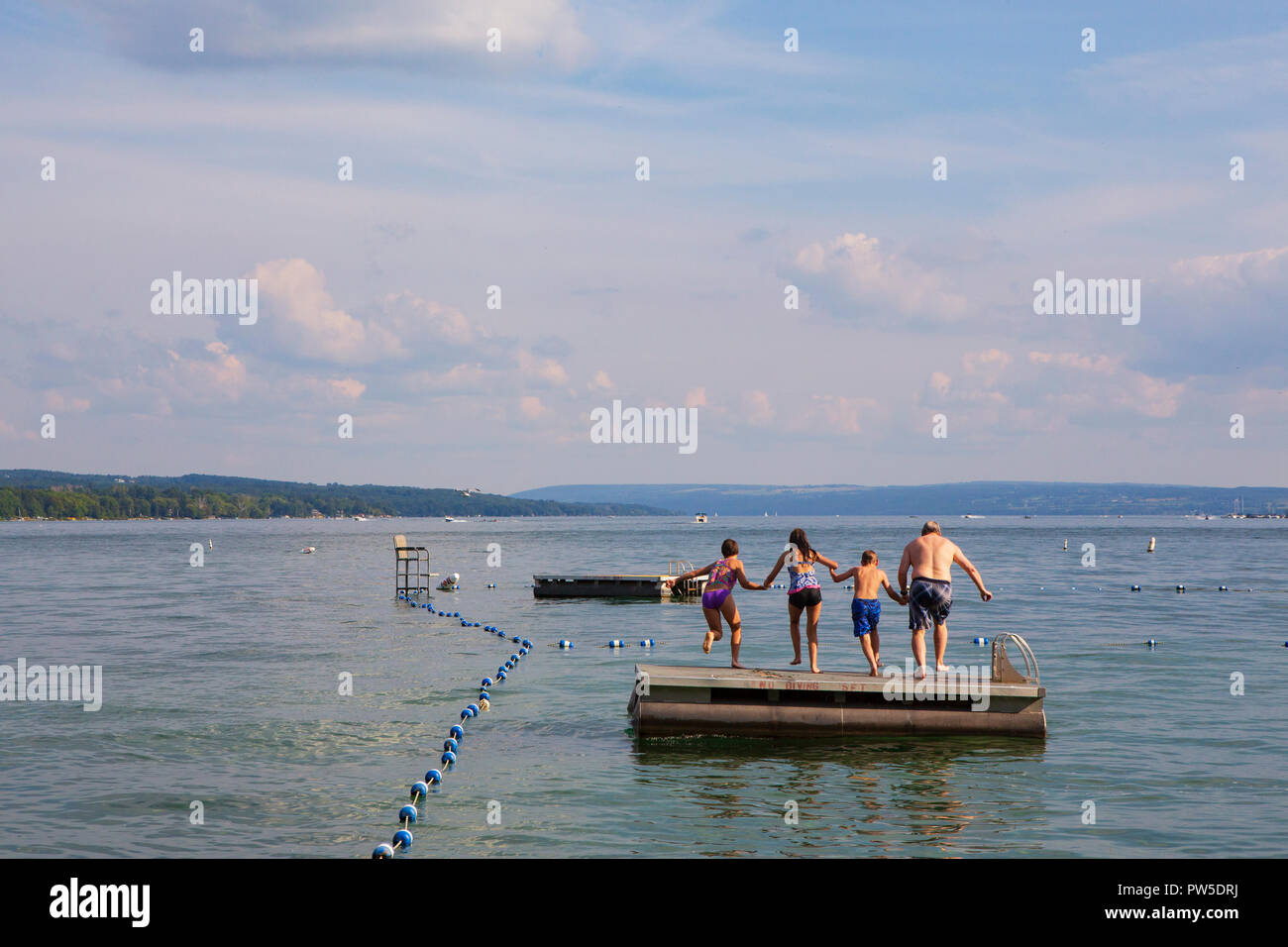 Una famiglia salti in Lago Skaneateles, Skaneateles, New York, Stati Uniti d'America, 14 giugno 2013. Foto Stock