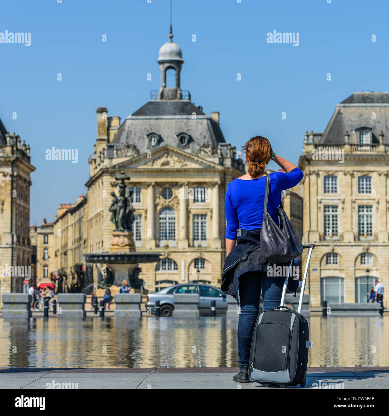 Donna con una valigia in Exchange Square, Bordeaux, Francia. Vista posteriore Foto Stock