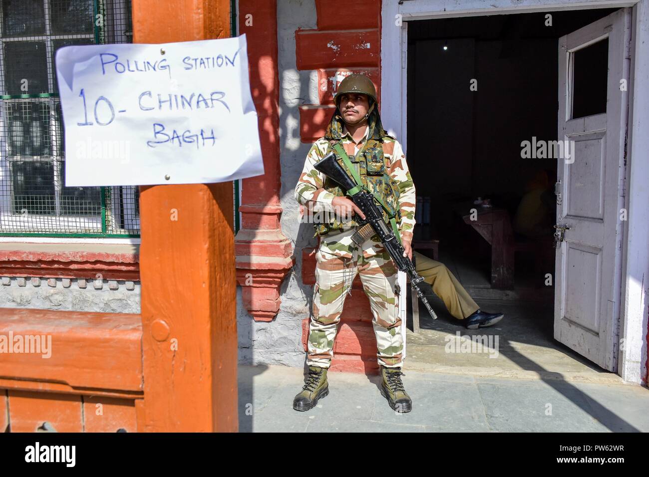 Ottobre 13, 2018 - Srinagar, J&K, India - un soldato di paramilitari avviso sorge al di fuori della stazione di polling durante la terza fase delle elezioni locali in Srinagar, Indiano Kashmir amministrato. La terza fase del Jammu e Kashmir urbano corpo locale elezioni ha cominciato attraverso 300 seggi alle 6 di mattina del sabato in mezzo alle severe misure di sicurezza. Come molti come 365 candidati sono in mischia per le elezioni. Una spessa coltre di sicurezza è stata gettata intorno ai seggi, mentre le forze di sicurezza stanno conducendo dominazione area di esercizi per garantire un incidente-libera elezione, hanno detto i funzionari. (Credito Foto Stock