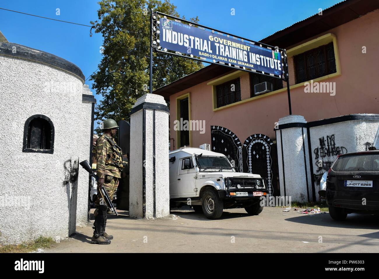 Ottobre 13, 2018 - Srinagar, J&K, India - un soldato di paramilitari avviso sorge al di fuori della stazione di polling durante la terza fase delle elezioni locali in Srinagar, Indiano Kashmir amministrato. La terza fase del Jammu e Kashmir urbano corpo locale elezioni ha cominciato attraverso 300 seggi alle 6 di mattina del sabato in mezzo alle severe misure di sicurezza. Come molti come 365 candidati sono in mischia per le elezioni. Una spessa coltre di sicurezza è stata gettata intorno ai seggi, mentre le forze di sicurezza stanno conducendo dominazione area di esercizi per garantire un incidente-libera elezione, hanno detto i funzionari. (Credito Foto Stock