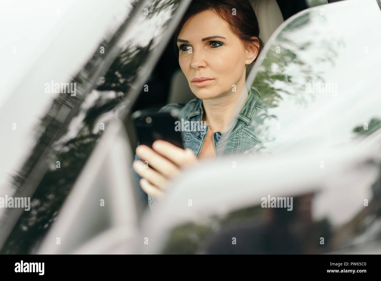 Imprenditrice texting mentre si guida per lavorare in auto Foto Stock