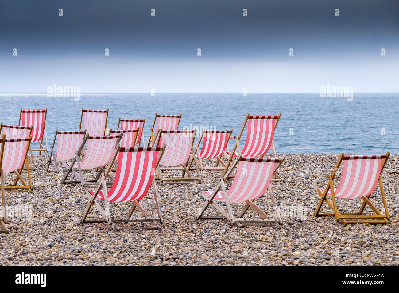 Svuotare sdraio sulla spiaggia di ciottoli di birra nel Devon. Foto Stock