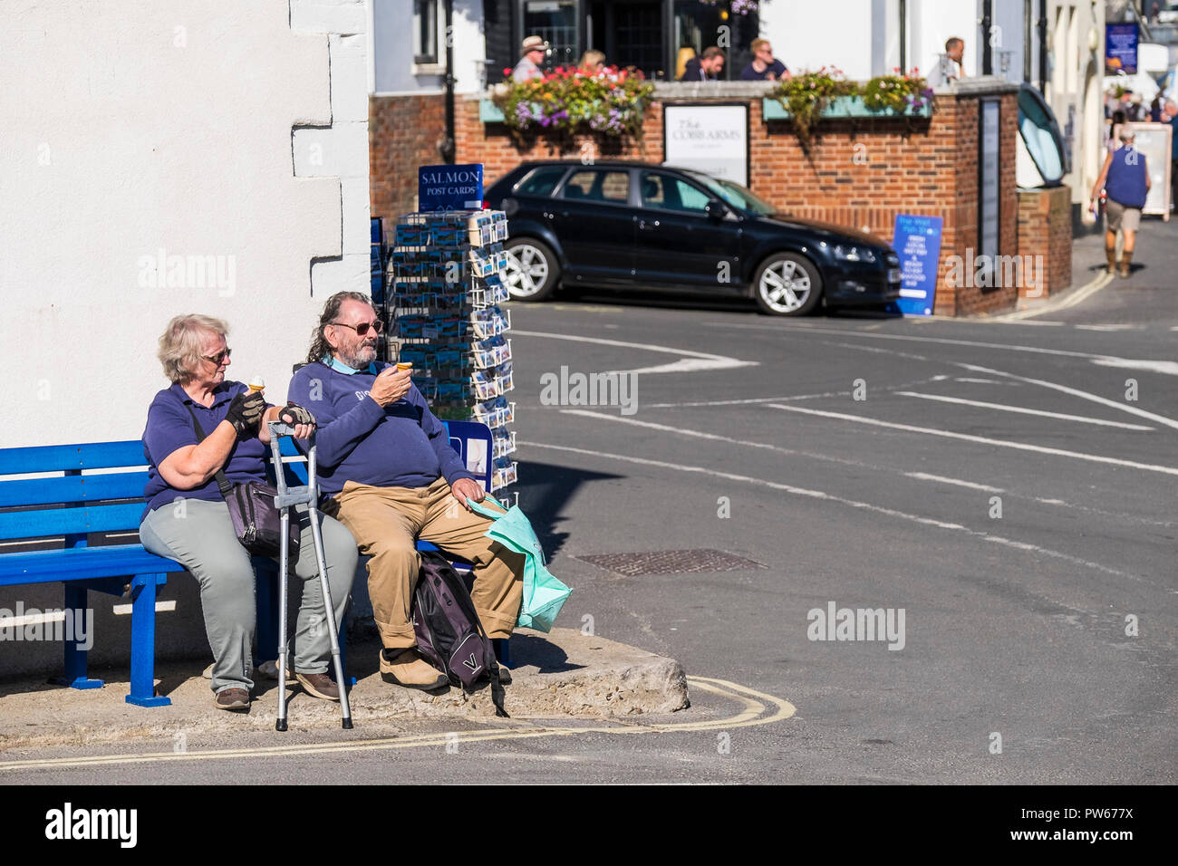 I vacanzieri maturo e rilassante godendo di un gelato e il sole nella città costiera di Lyme Regis nel Dorset. Foto Stock