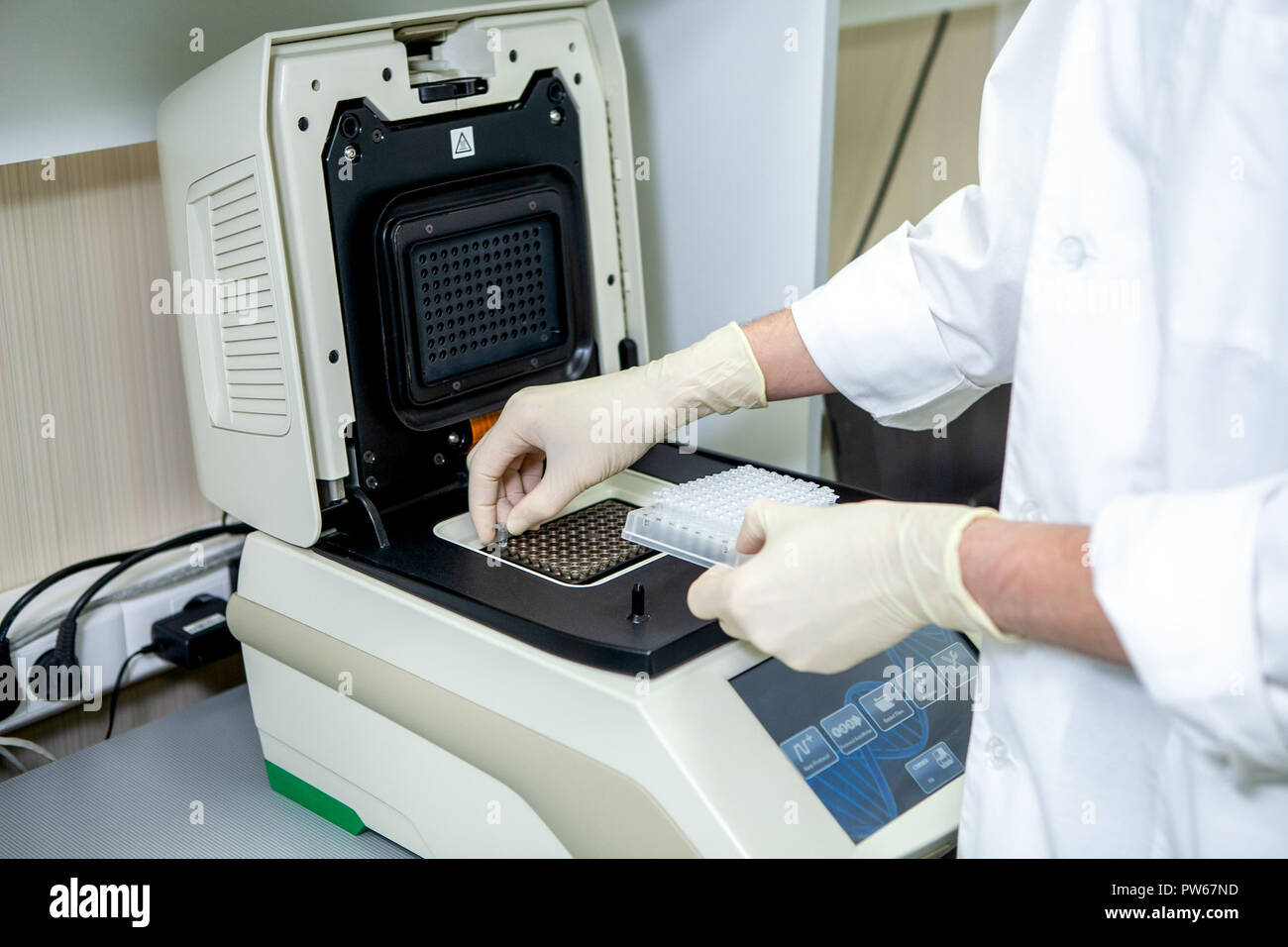 Una specialista di laboratorio luoghi provette con campioni di prova in una speciale apparecchiatura per lo studio della composizione Foto Stock