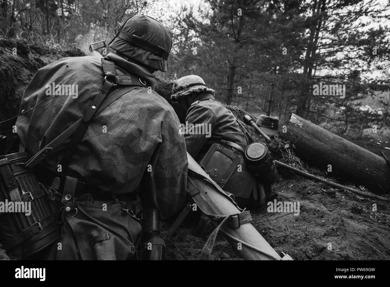 Unidentified Re-enactors vestito come il tedesco della Wehrmacht soldati di fanteria nella guerra mondiale II seduta nascosta con il tedesco hand-held Anti-serbatoio Lanciagranate Foto Stock