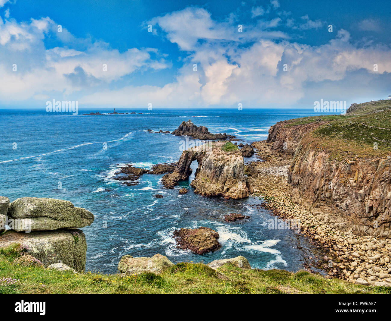 Costa rocciosa di Lands End, Cornwall, Regno Unito, con l'arco, Enys Dodnan, e la formazione di roccia del Cavaliere armato con la Longships Lighthouse offshor Foto Stock
