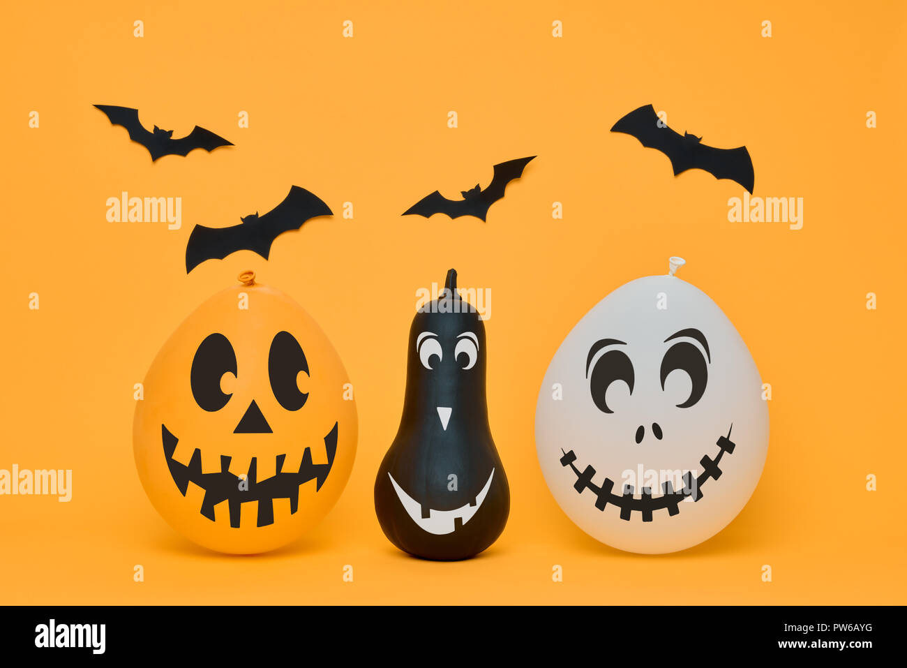 Carino zucche di Halloween divertente con volti sorridenti e carta pipistrelli volare sopra lo sfondo arancione. Concetto di Halloween. Foto Stock