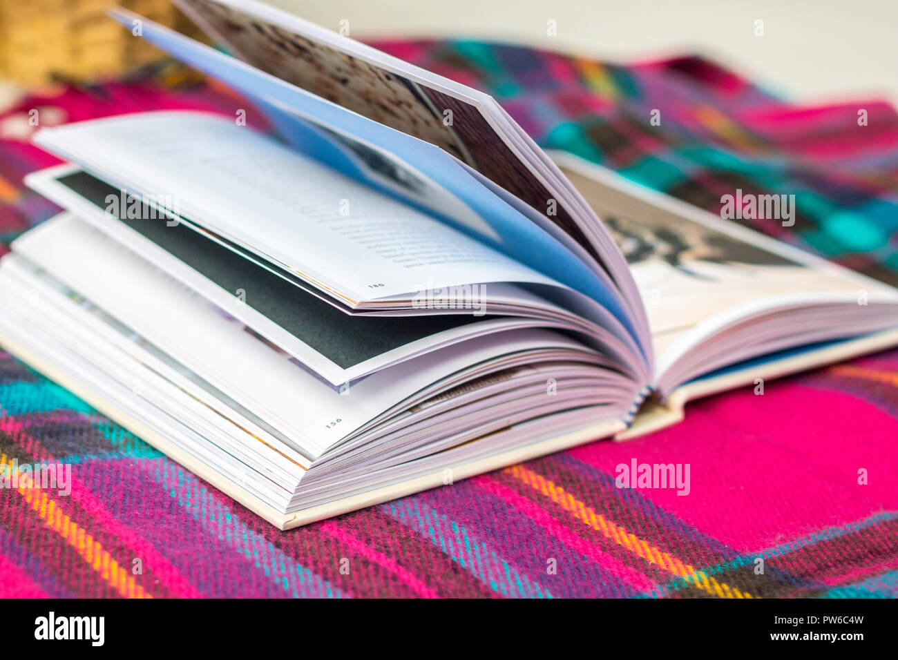 Coperta di tartan libro aperto su un tavolo giardino all'aperto, mock up, flatlay, timeout concetto, hygge, lo stile di vita facile vivere, vita migliore, rilassante atmosfera rilassata Foto Stock