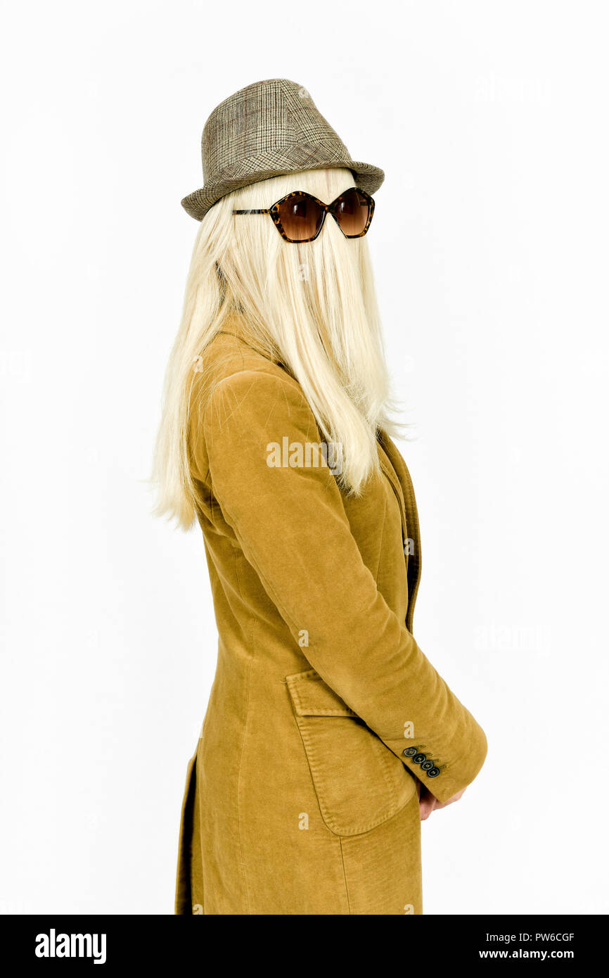 Fun immagine di donna con capelli lunghi biondi che ricopre la faccia e occhiali da sole a giocare vestire per Halloween come Cugino ITT Foto Stock