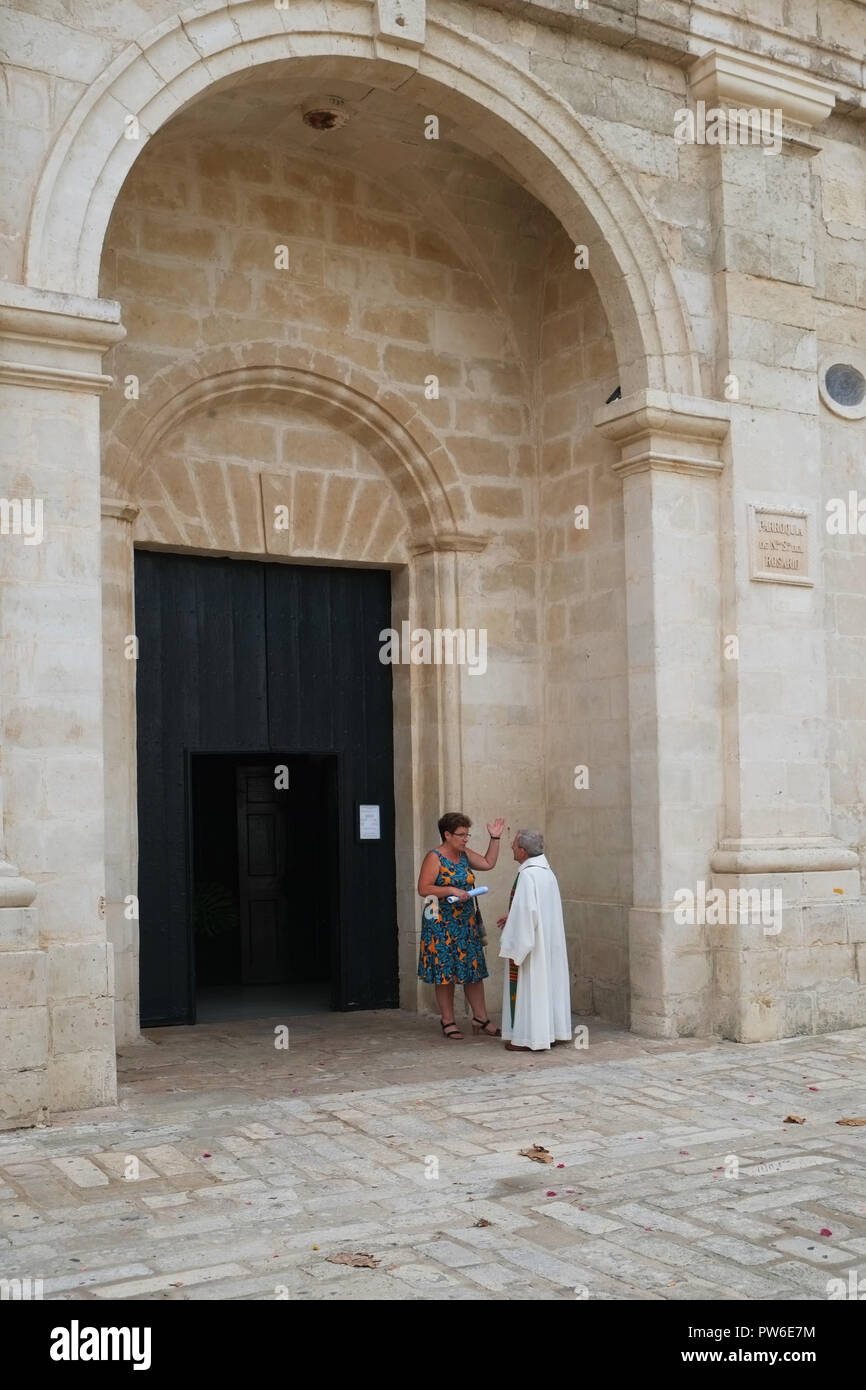 Un prete cattolico parla di un membro della Congregazione dopo la messa domenicale a Parroquia de Nuestra Señora del Rosario, Es Castell, Menorca, Spagna Foto Stock
