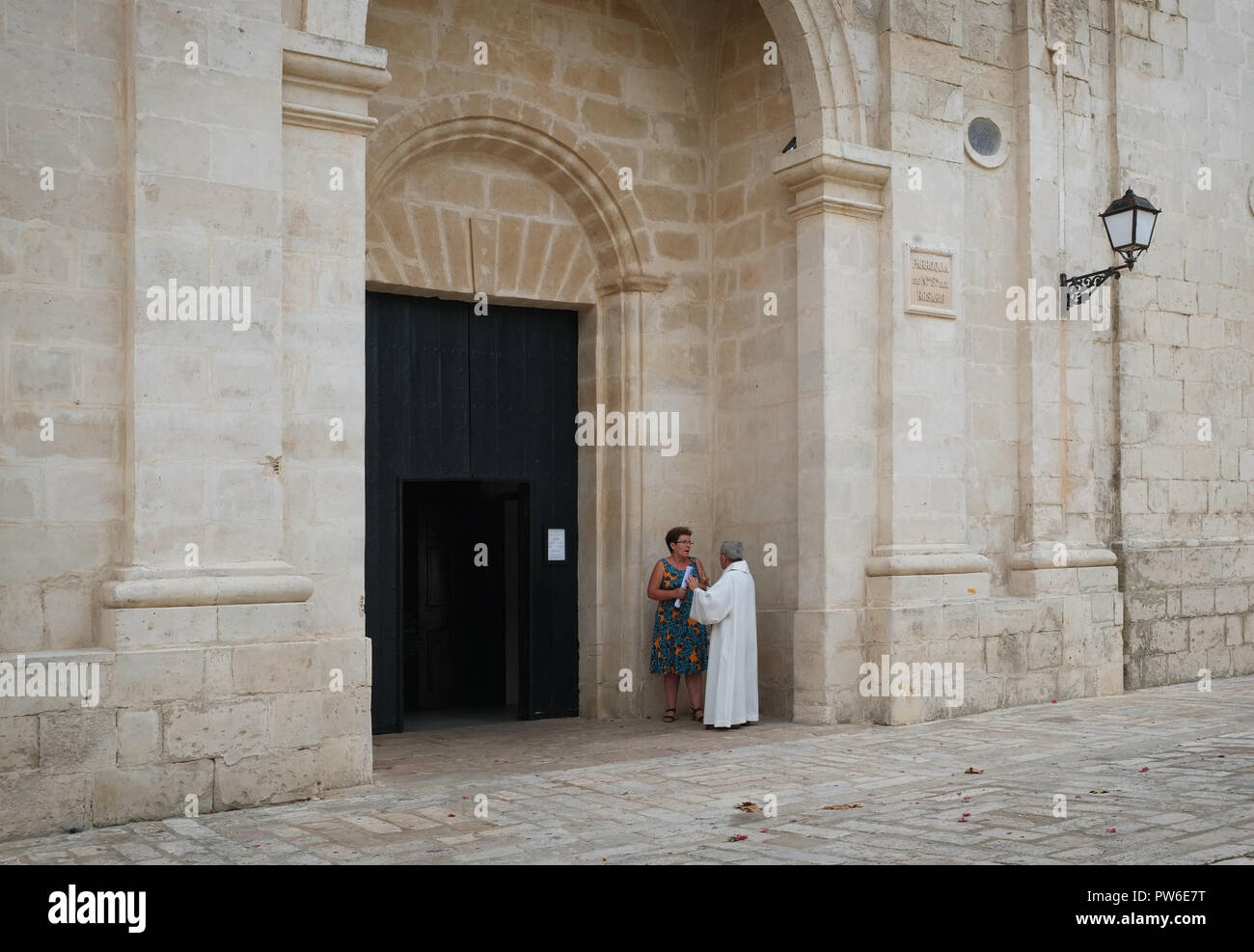 Un prete cattolico parla di un membro della Congregazione dopo la messa domenicale a Parroquia de Nuestra Señora del Rosario, Es Castell, Menorca, Spagna Foto Stock
