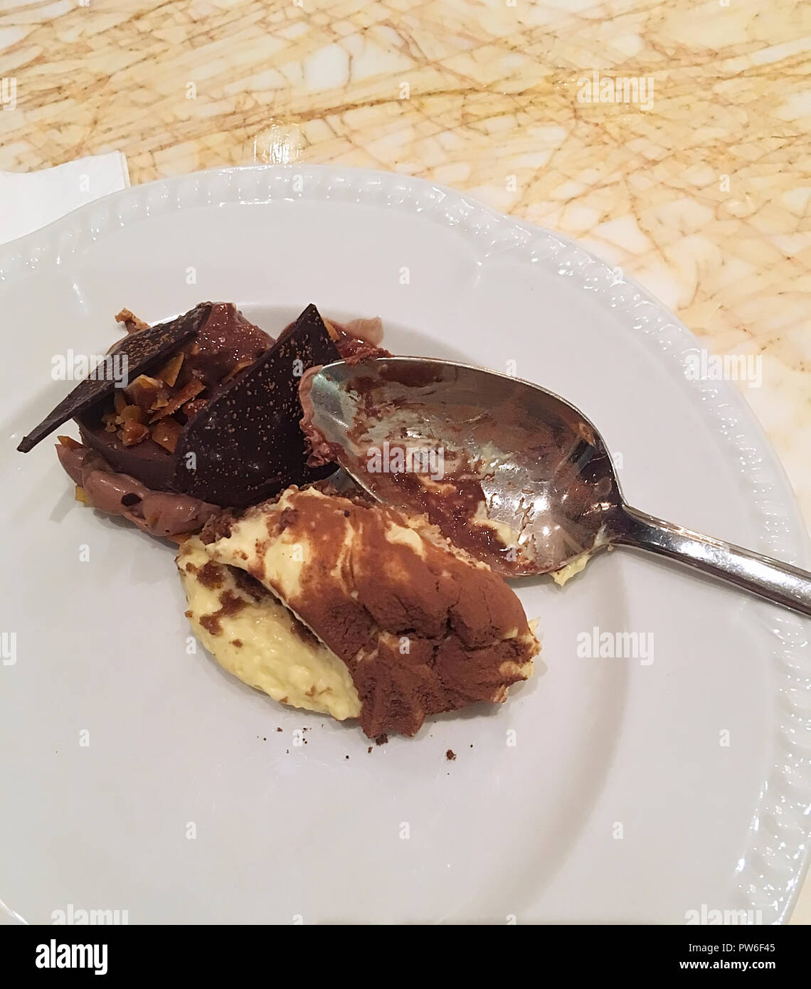 Cremoso budino di cioccolato pronto a mangiare su una piastra bianca con cucchiaio d'argento. Primo piano. Foto Stock