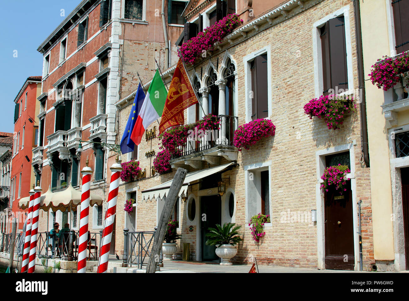Bandiere, scatole di finestra, pali di ormeggio, balconi e fiori tipici ornamenti per essere trovato su edifici della città italiana di Venezia. Foto Stock