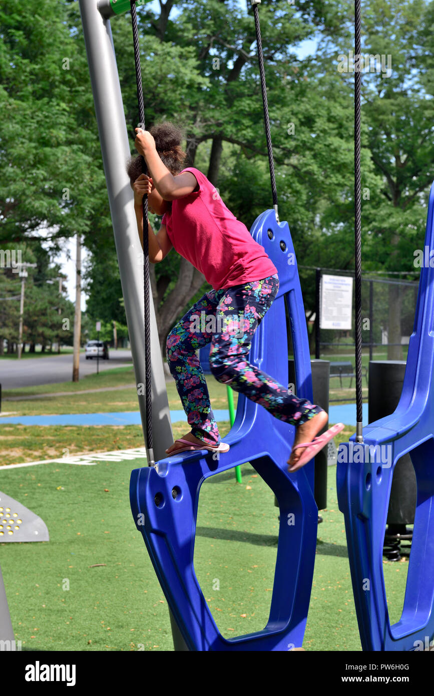 Ragazza giovane arrampicate sulle attrezzature per il gioco nel parco pubblico, Rochester, New York, Stati Uniti d'America Foto Stock