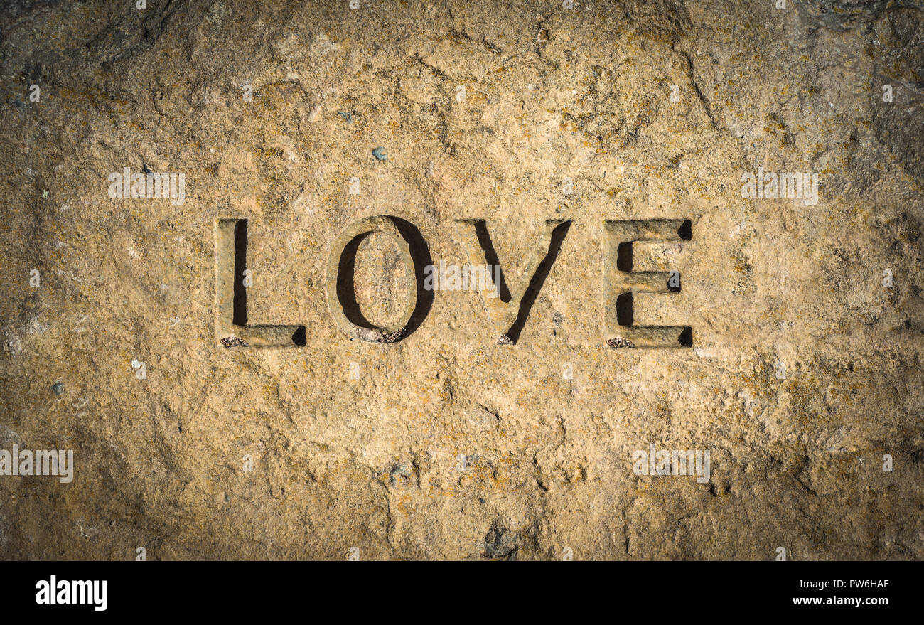 Immagine concettuale della parola amore cesellato in pietra o roccia Foto Stock