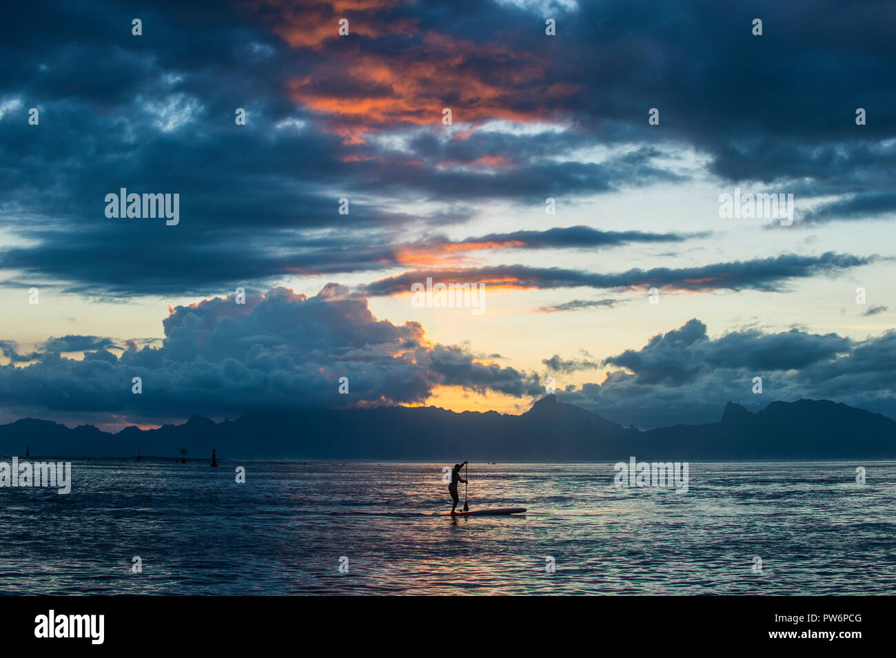 Silhouette di un stand up paddler, drammatico tramonto su Moorea, Papeete, Tahiti Foto Stock