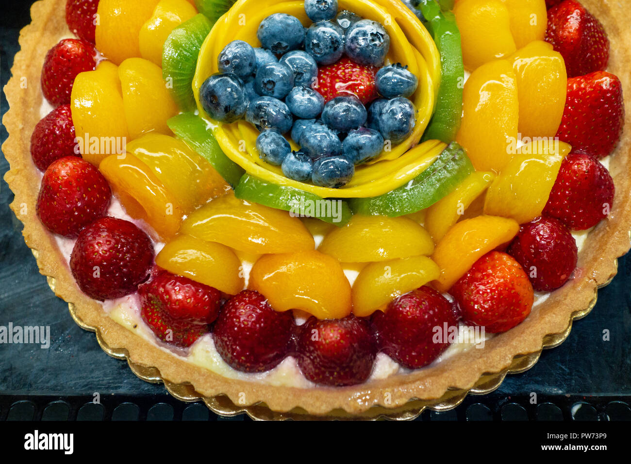 Grande cotta crostata di frutta al mercato display con il rosso, il viola, giallo, verde Foto Stock