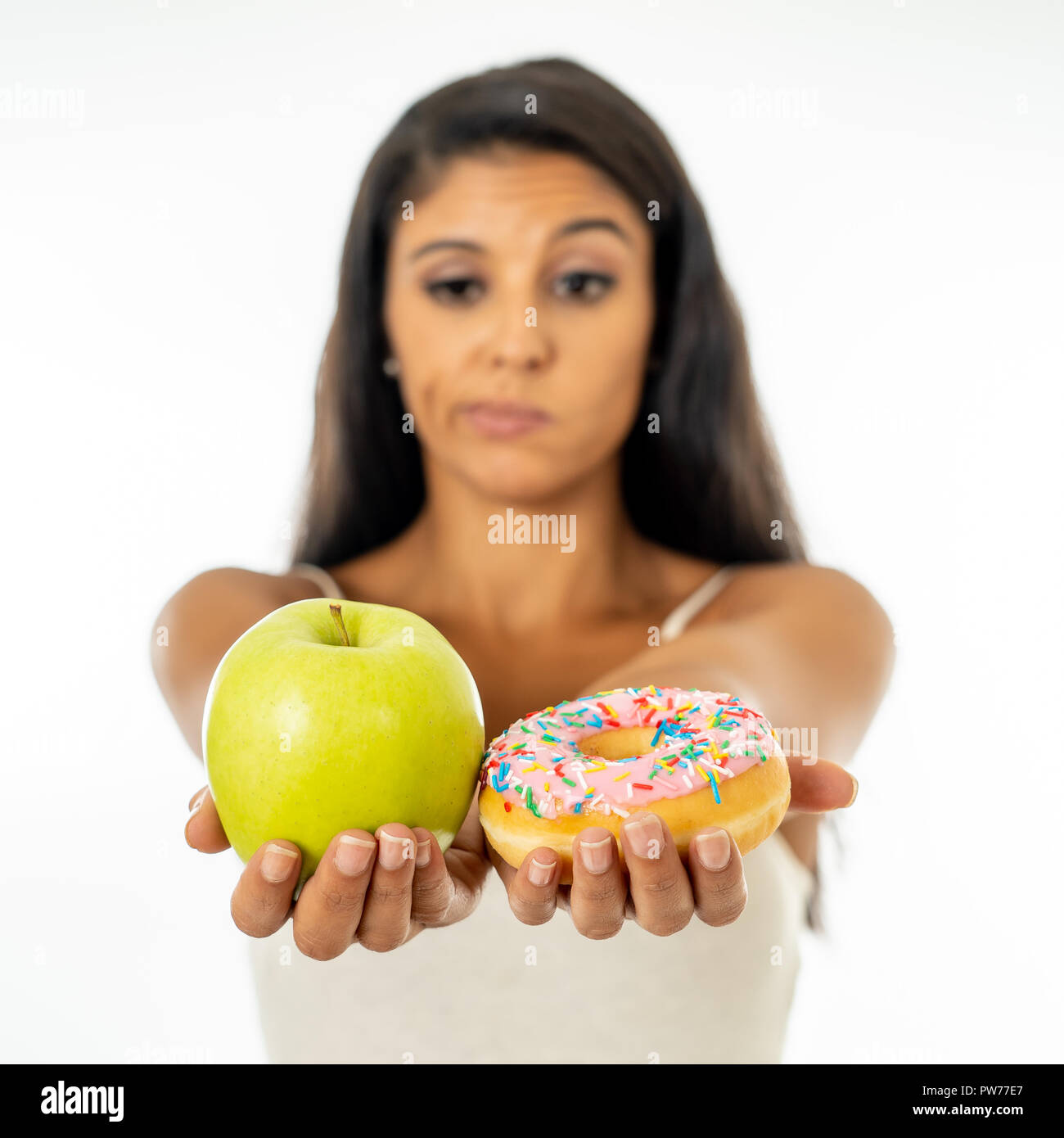 Bella giovane donna tentati di dover fare una scelta tra apple e la ciambella in sano cibo malsano, detox mangiare, calorie e il concetto di dieta. Foto Stock Bella giovane donna tentati di dover fare una scelta tra apple e la ciambella in sano cibo malsano, detox mangiare, calorie e il concetto di dieta. Foto Stock
