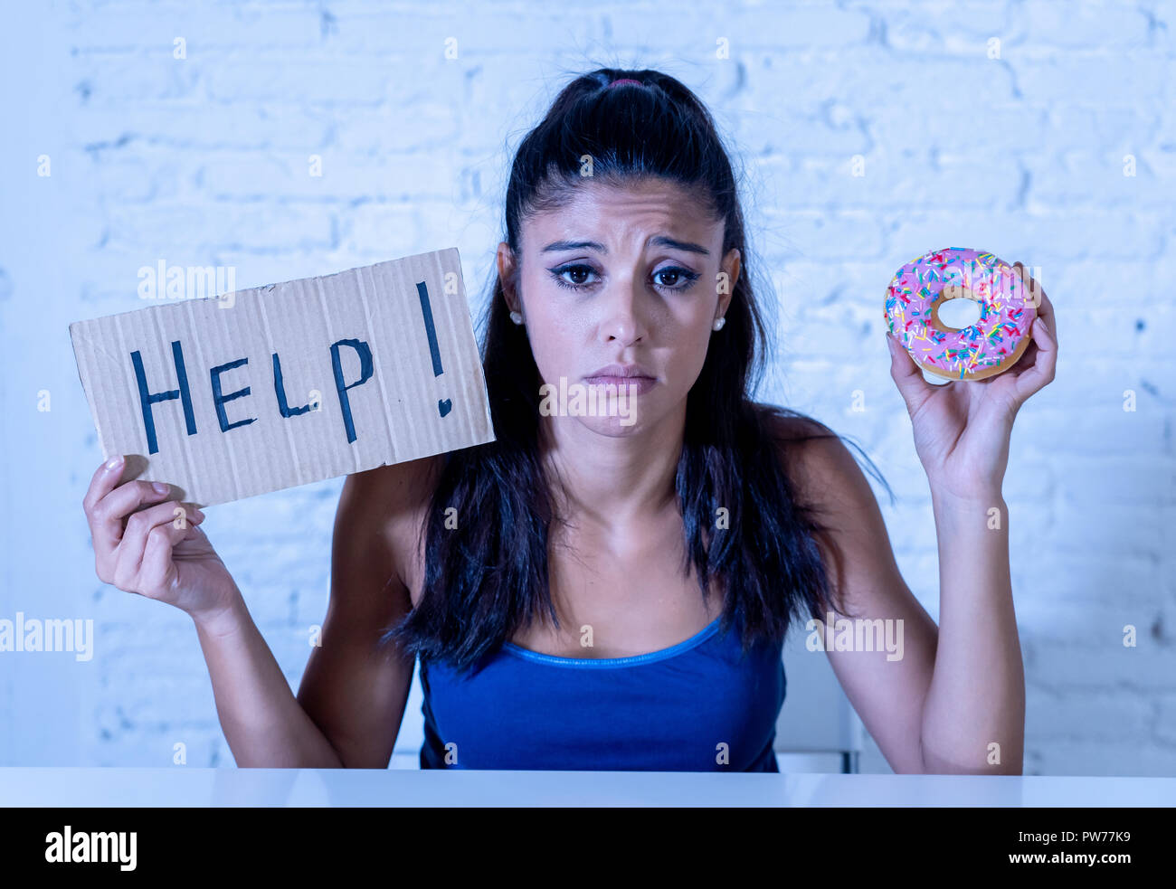Giovani preoccupati latino sentimento donna tentati e colpevole che vogliono mangiare cioccolato e ciambelle per chiedere aiuto nella dieta calorie zucchero nutrizione della tossicodipendenza un Foto Stock