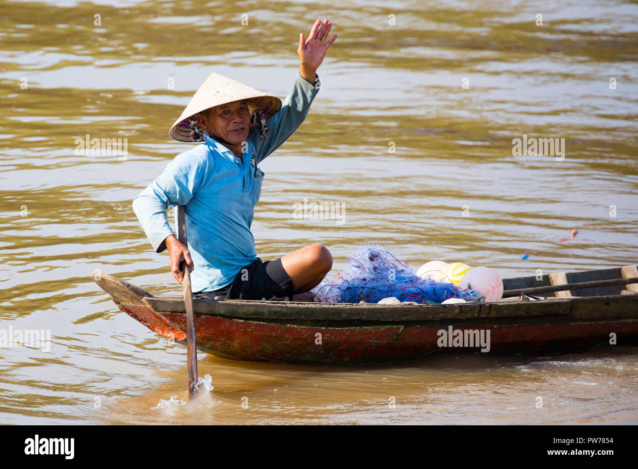 Delta del Mekong, Vietnam - 28 Settembre 2018: Unidentified pescatore locale nella sua barca onde felicemente sul fiume Mekong in Vietnam. Foto Stock