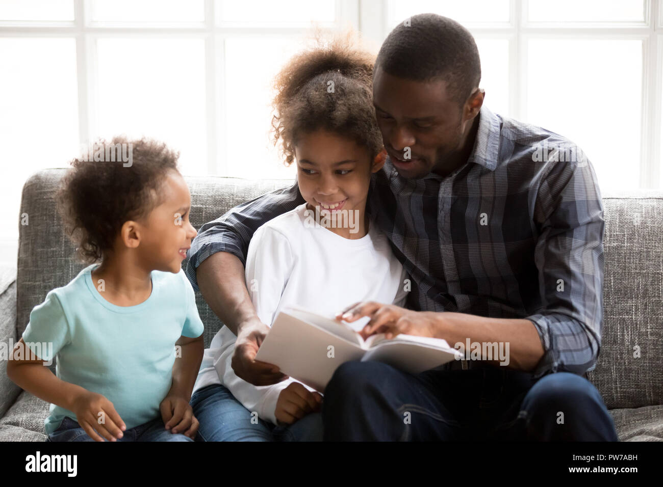 Padre con i bambini a leggere un libro a casa Foto Stock
