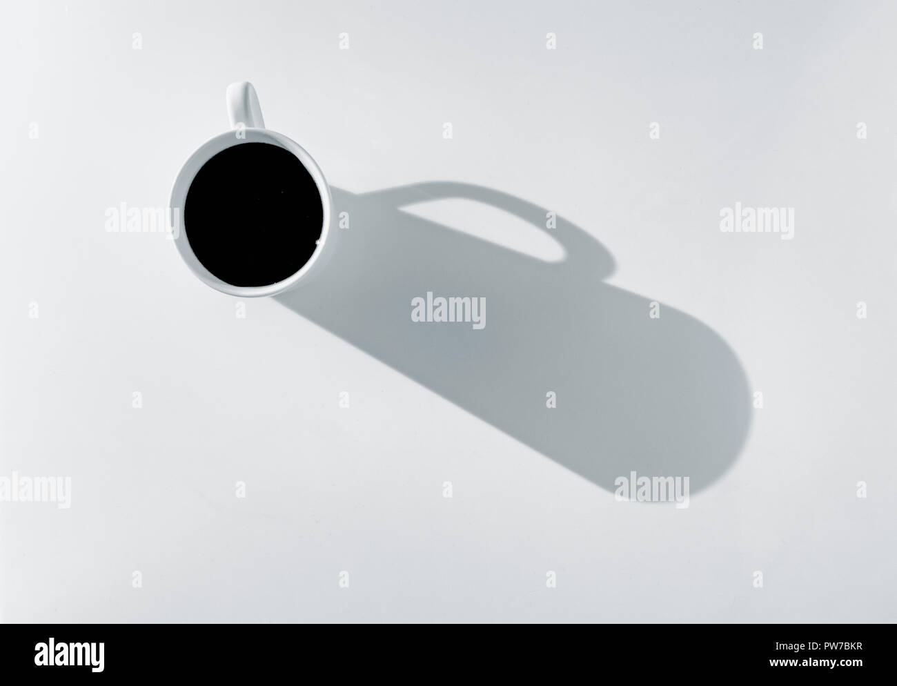Caffè in tazza su uno sfondo bianco, la colata di una forte ombra in questa alta foto chiave. Foto Stock