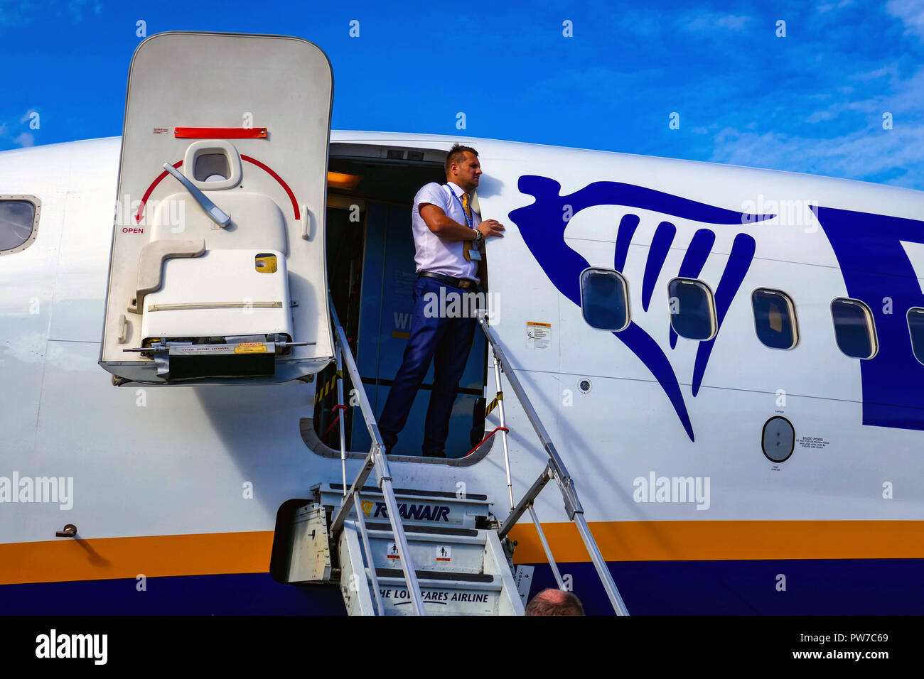 Aria maschio host, equipaggio di cabina, apre il portello, guardando fuori, Ryanair Boeing 737 a Londra Stansted Airport, Foto Stock