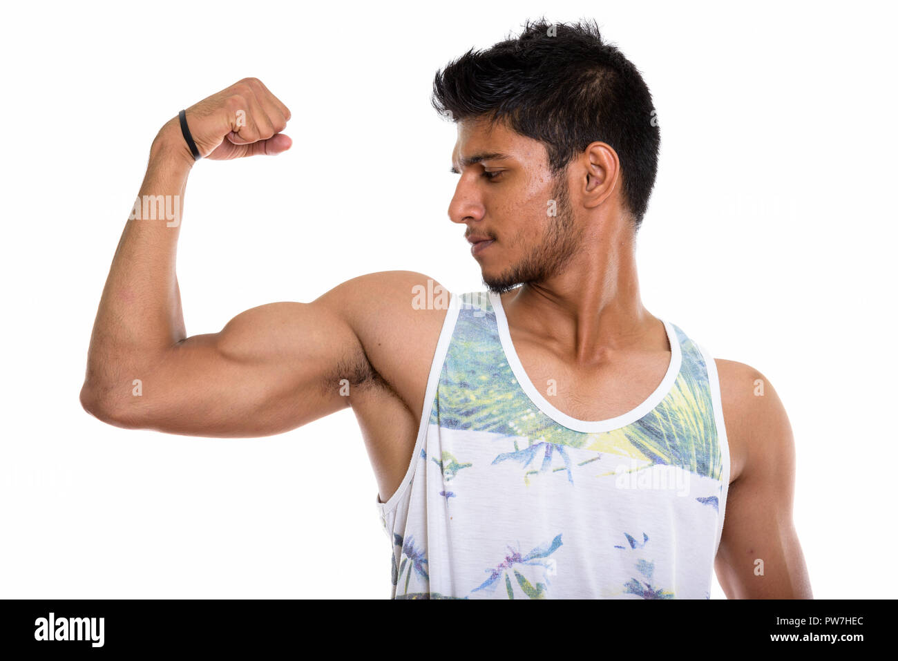 Vista di profilo del giovane bello uomo indiano flettendo il suo braccio Foto Stock