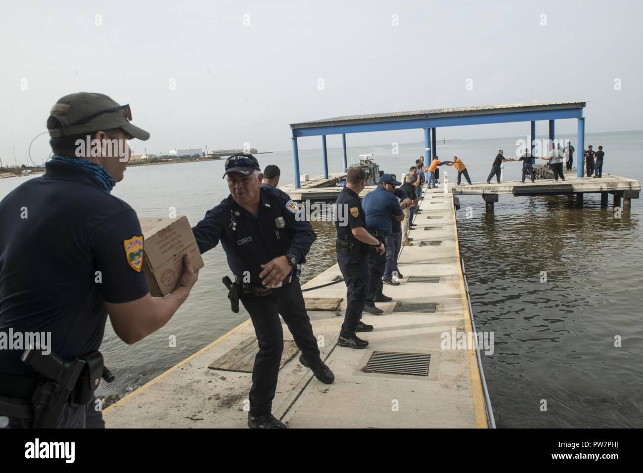 Una catena umana fatta di Coast Guard, locali, statali e federali di funzionari lavorano insieme per alleggerire il cibo fornito dal personale dei guardacoste Venturous presso un porto turistico vicino a Ponce, Puerto Rico, Mercoledì, Settembre 27, 2017. Foto Stock