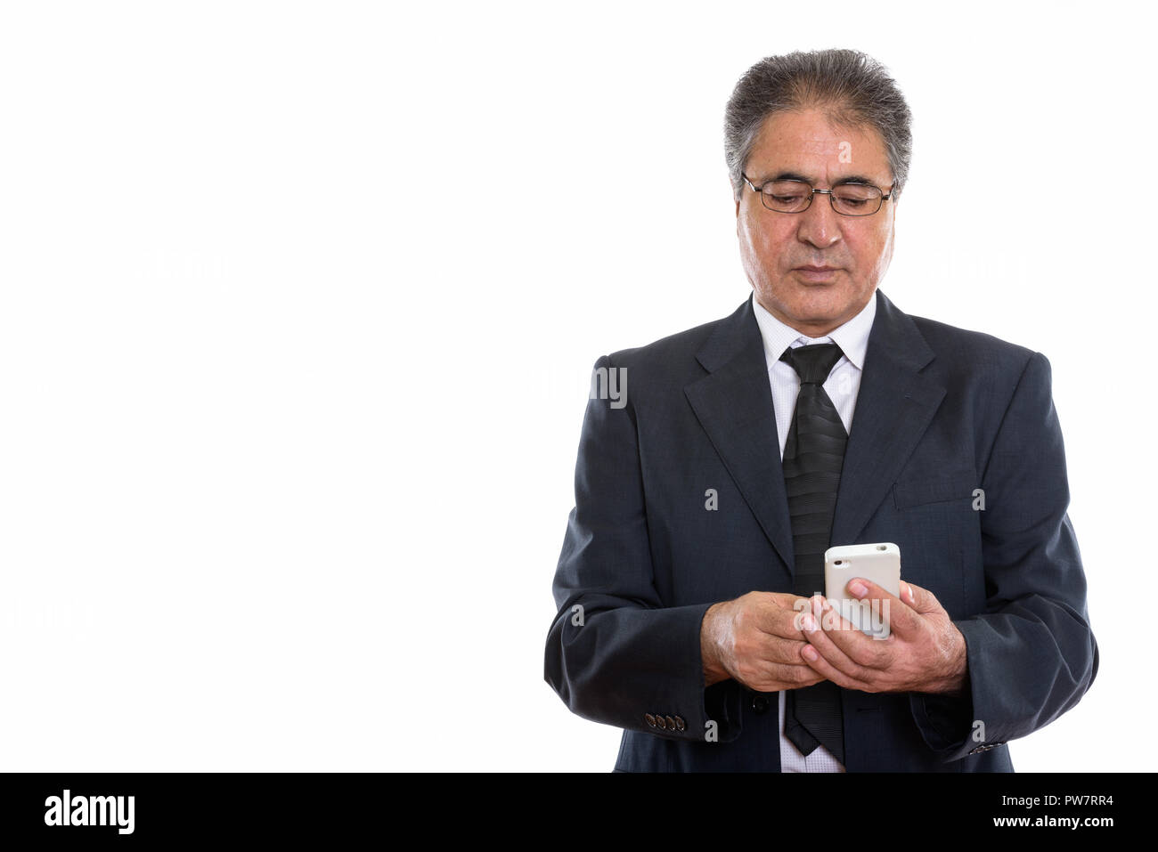 Studio shot di senior imprenditore persiano utilizzando il telefono cellulare Foto Stock