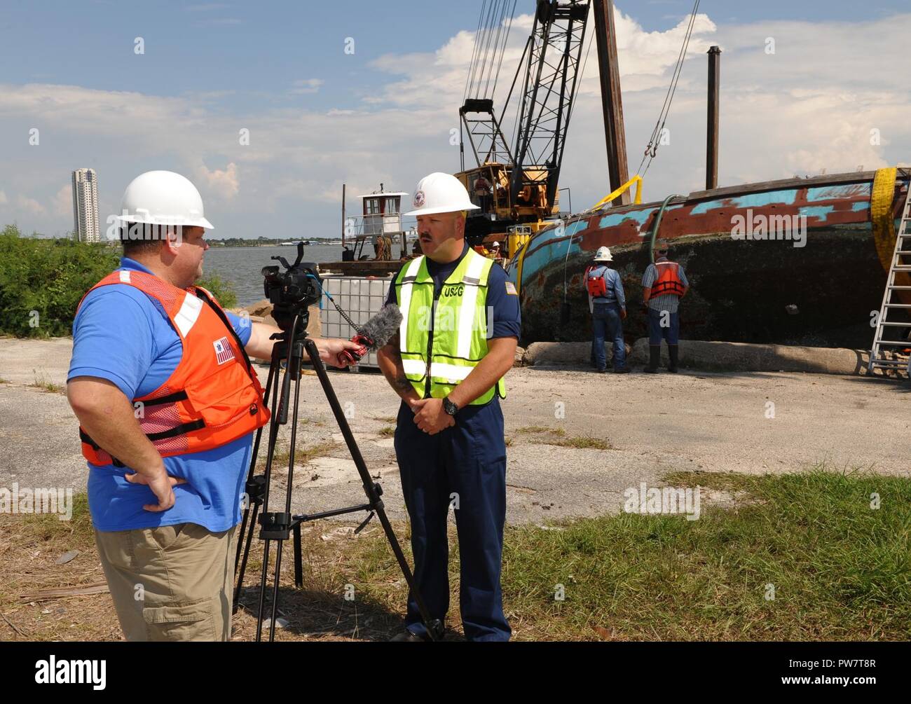 Coast Guard Petty Officer di prima classe Tindol Bret del Golfo Strike Team offre un'intervista a reporter locale Kar Hlava di MI45ora qui a Houston, Texas, sul Sett. 28, 2017. Il Coast Guard, il Texas terra generale Ufficio, il Texas Commissione sulla qualità dell'ambiente e l'Agenzia per la protezione ambientale sono stati completamente integrati in un comando unificato con la missione assegnazione di rimozione spostato o parzialmente sommerso le navi come un risultato di uragano Harvey. Foto Stock