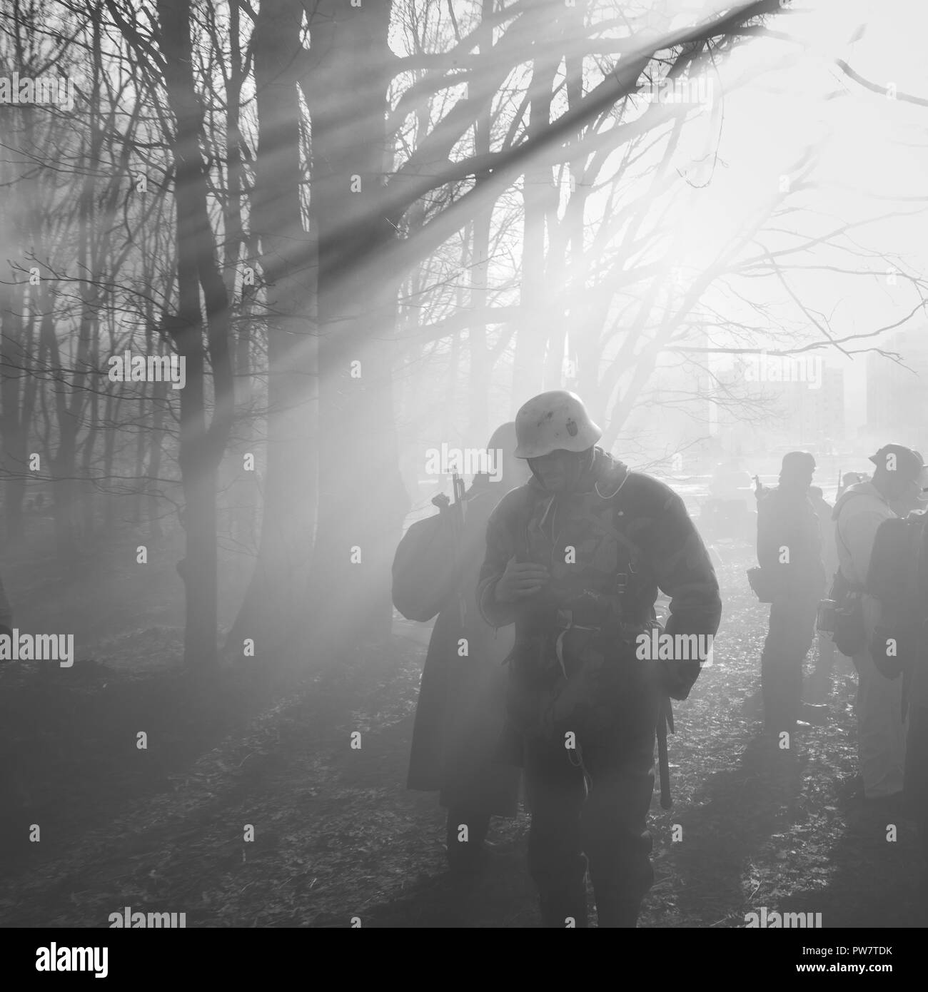 Re-enactors vestito come il tedesco della Wehrmacht Soldato di fanteria nella guerra mondiale II in piedi nella retroilluminazione drammatico attraverso il fumo durante la rievocazione storica. P Foto Stock