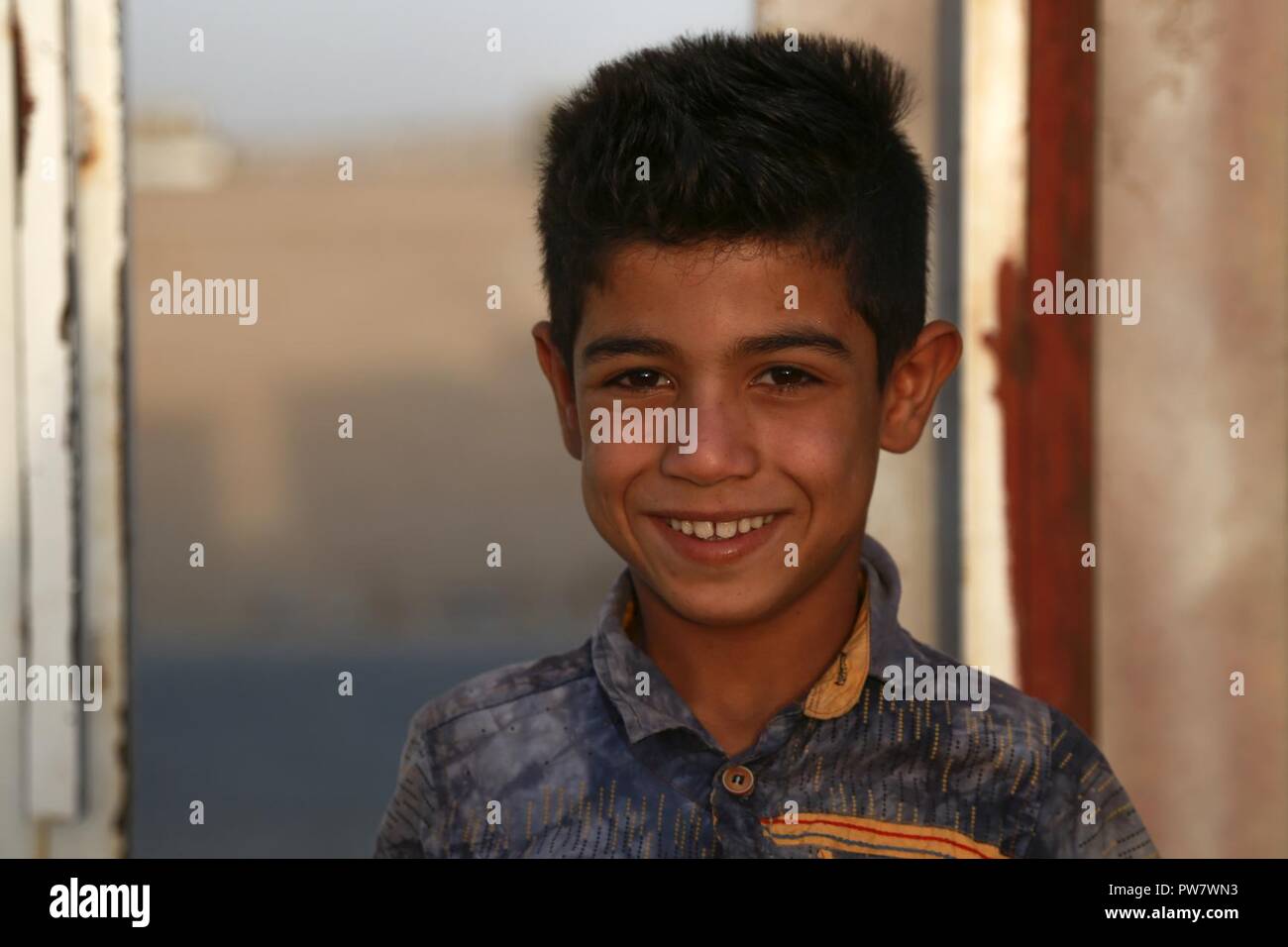 Un giovane ragazzo in posa per una foto ad un gate di un internamente sfollati persona punto di screening in Hajj Ali, Iraq, 27 settembre 2017. Foto Stock