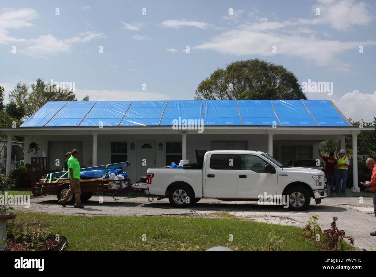 SEBRING, Fla. -- appaltatori pack di materiali e di marcia dopo l'installazione di materia plastica rinforzata con fibra di pacciamatura su un uragano Irma-tetto danneggiato a Sebring, Florida 1 Ottobre, 2017. I contraenti sono stati noleggiati da parte del governo degli STATI UNITI Esercito di tecnici per il funzionamento del tetto blu. Il programma invia gli appaltatori con licenza per installare blue teli in plastica sui tetti ammissibili fino a quando i residenti possono organizzare le riparazioni permanenti. Come di ottobre 2, 2017, il corpo ha installato più di 1300 "tetti blu" attraverso 29 contee della Florida. Foto Stock SEBRING, Fla. -- appaltatori pack di materiali e di marcia dopo l'installazione di materia plastica rinforzata con fibra di pacciamatura su un uragano Irma-tetto danneggiato a Sebring, Florida 1 Ottobre, 2017. I contraenti sono stati noleggiati da parte del governo degli STATI UNITI Esercito di tecnici per il funzionamento del tetto blu. Il programma invia gli appaltatori con licenza per installare blue teli in plastica sui tetti ammissibili fino a quando i residenti possono organizzare le riparazioni permanenti. Come di ottobre 2, 2017, il corpo ha installato più di 1300 "tetti blu" attraverso 29 contee della Florida. Foto Stock
