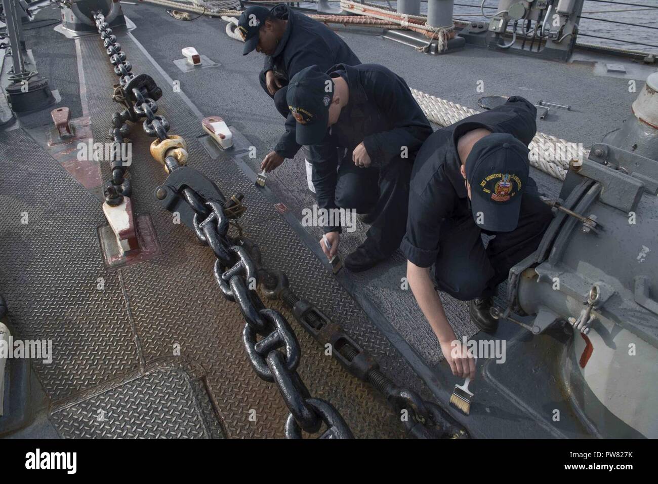 FASLANE in Scozia (sett. 30, 2017) i marinai a bordo del Arleigh Burke-class guidato-missile destroyer USS Winston S. Churchill (DDG 81) pittura il mazzo sett. 30, 2017. Churchill, homeported alla stazione navale di Norfolk, sta conducendo operazioni navali negli Stati Uniti Sesta flotta area di operazioni a sostegno degli Stati Uniti per gli interessi di sicurezza nazionali in Europa. Foto Stock