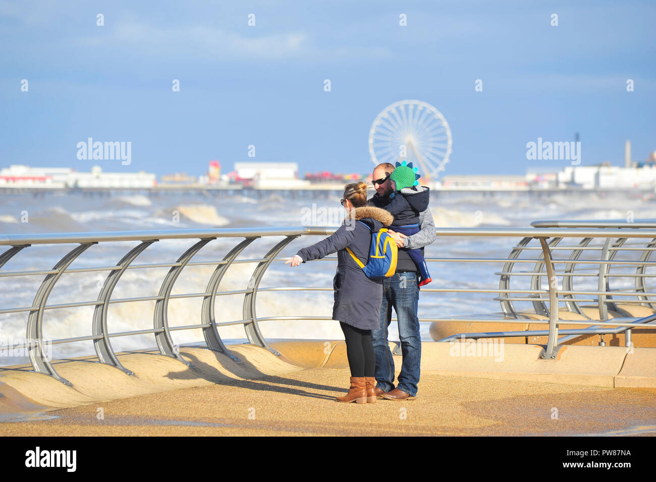 Famiglia giovane guardando la marea venite in sul lungomare di Blackpool su una soleggiata giornata di ottobre Foto Stock