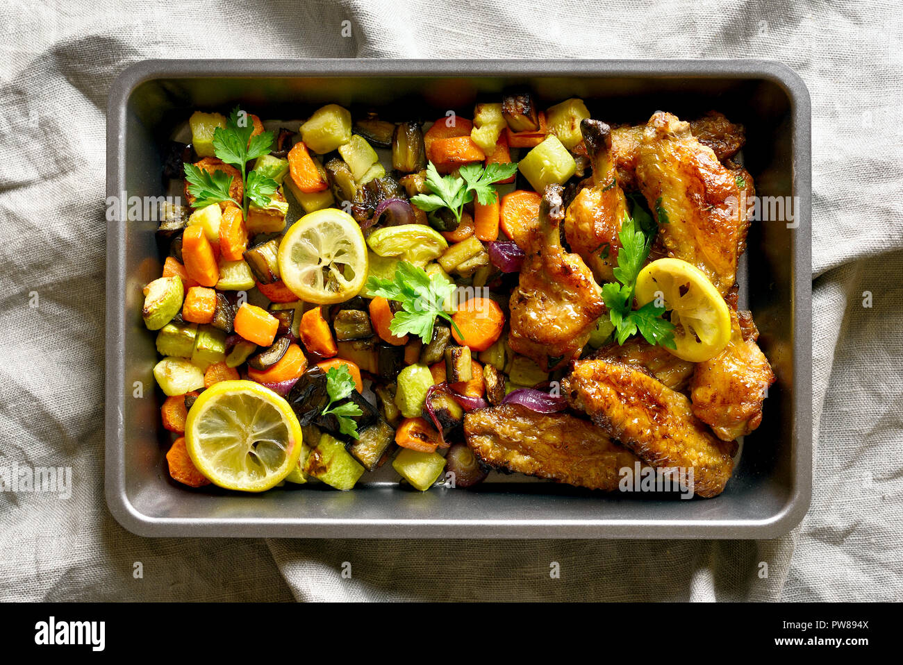 Piatto per la cena. Grigliata di ali di pollo con verdure nel vassoio da forno. Vista superiore, laici piatta Foto Stock