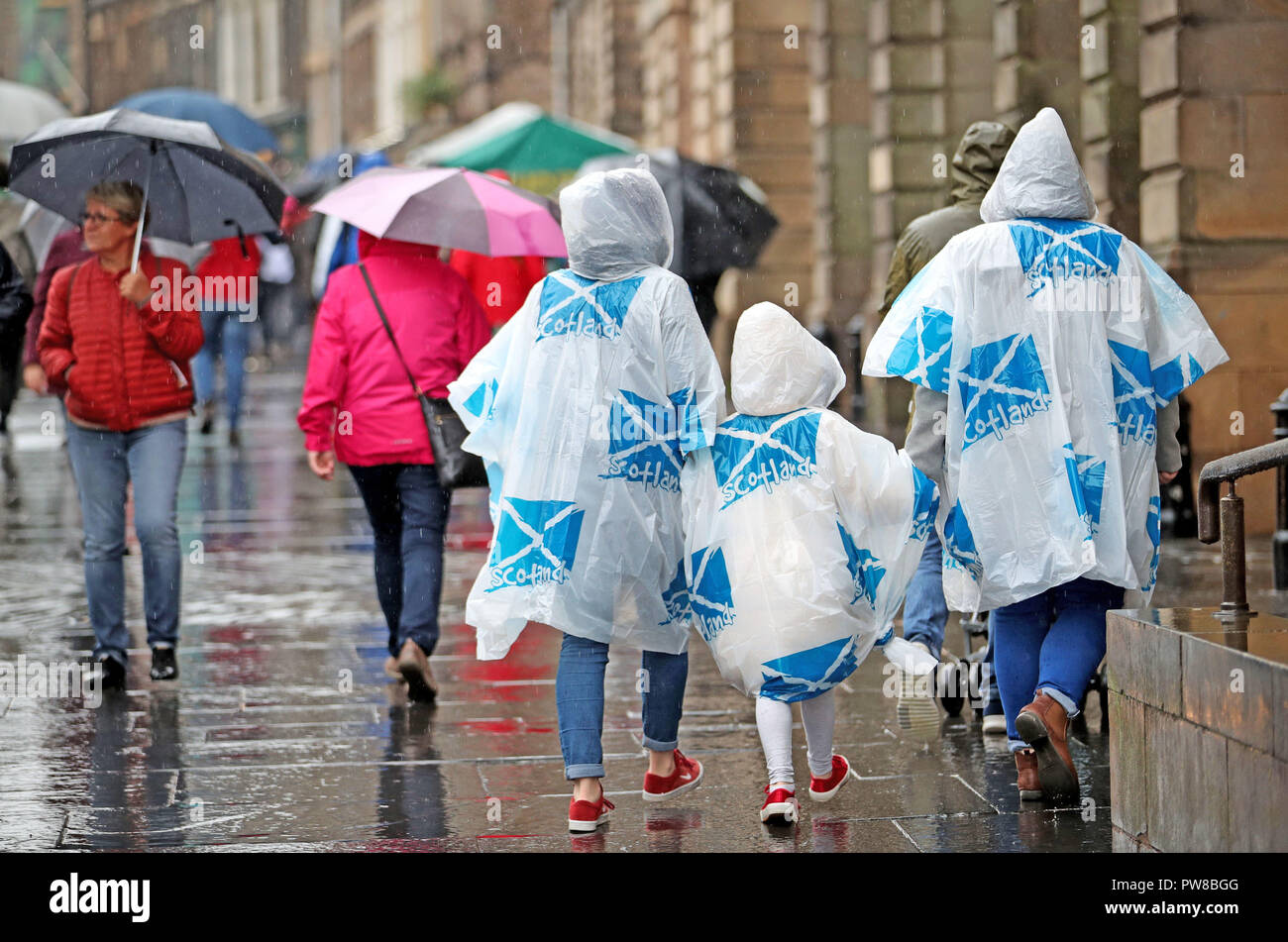 I turisti che indossa poncho di emergenza su Edinburgh Royal Mile. Foto Stock