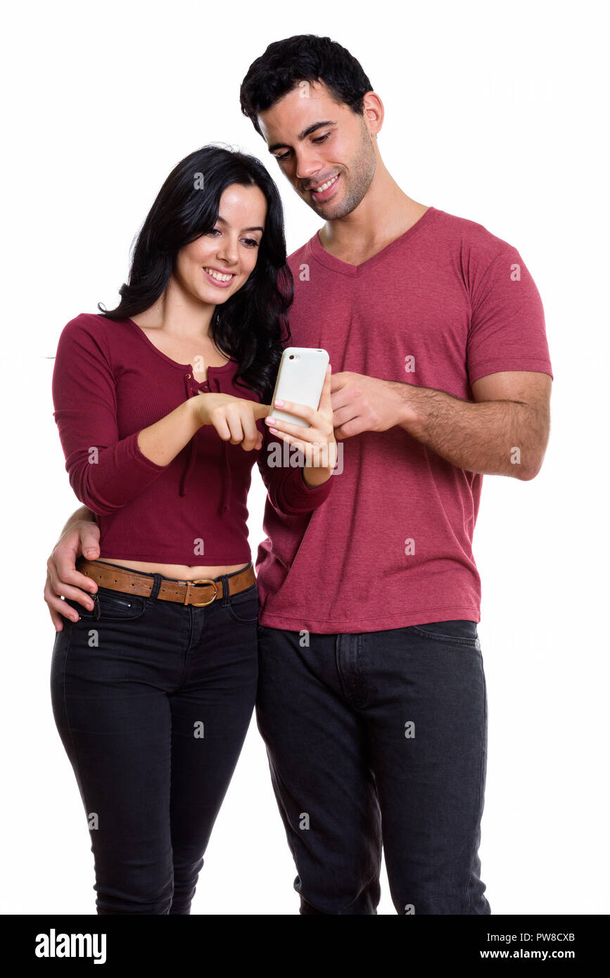 Studio shot della giovane coppia felice sorridere mentre utilizzando un mobile Foto Stock