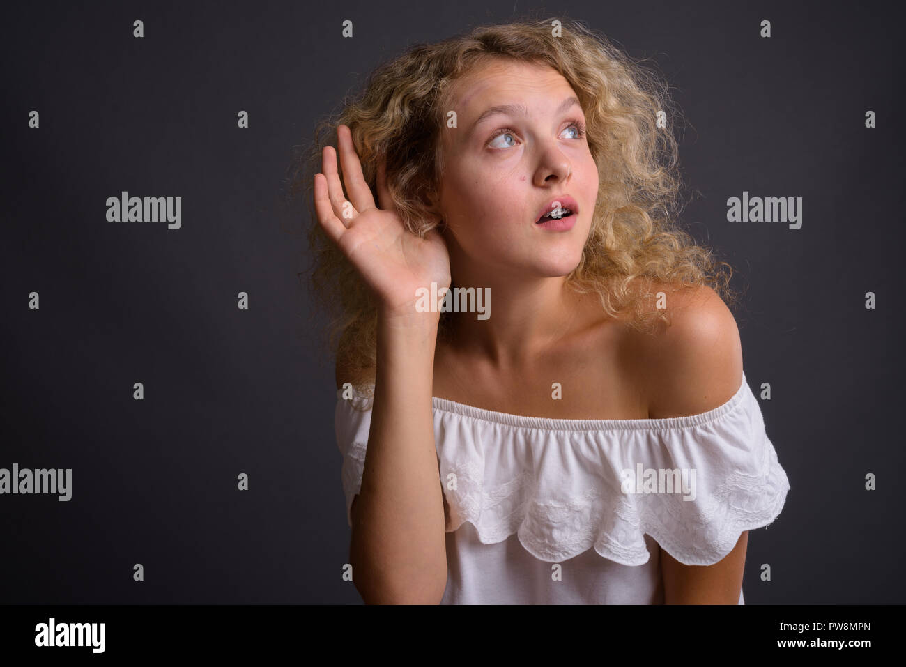 Giovane bella donna bionda con capelli ricci contro backgro grigio Foto Stock
