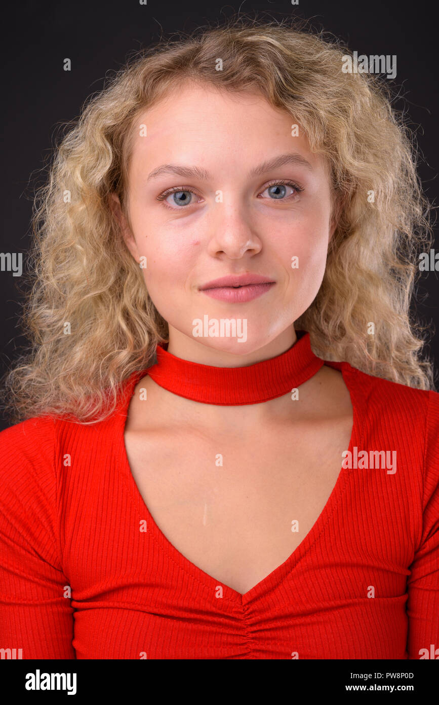 Giovane bella donna bionda con capelli ricci contro backgro grigio Foto Stock