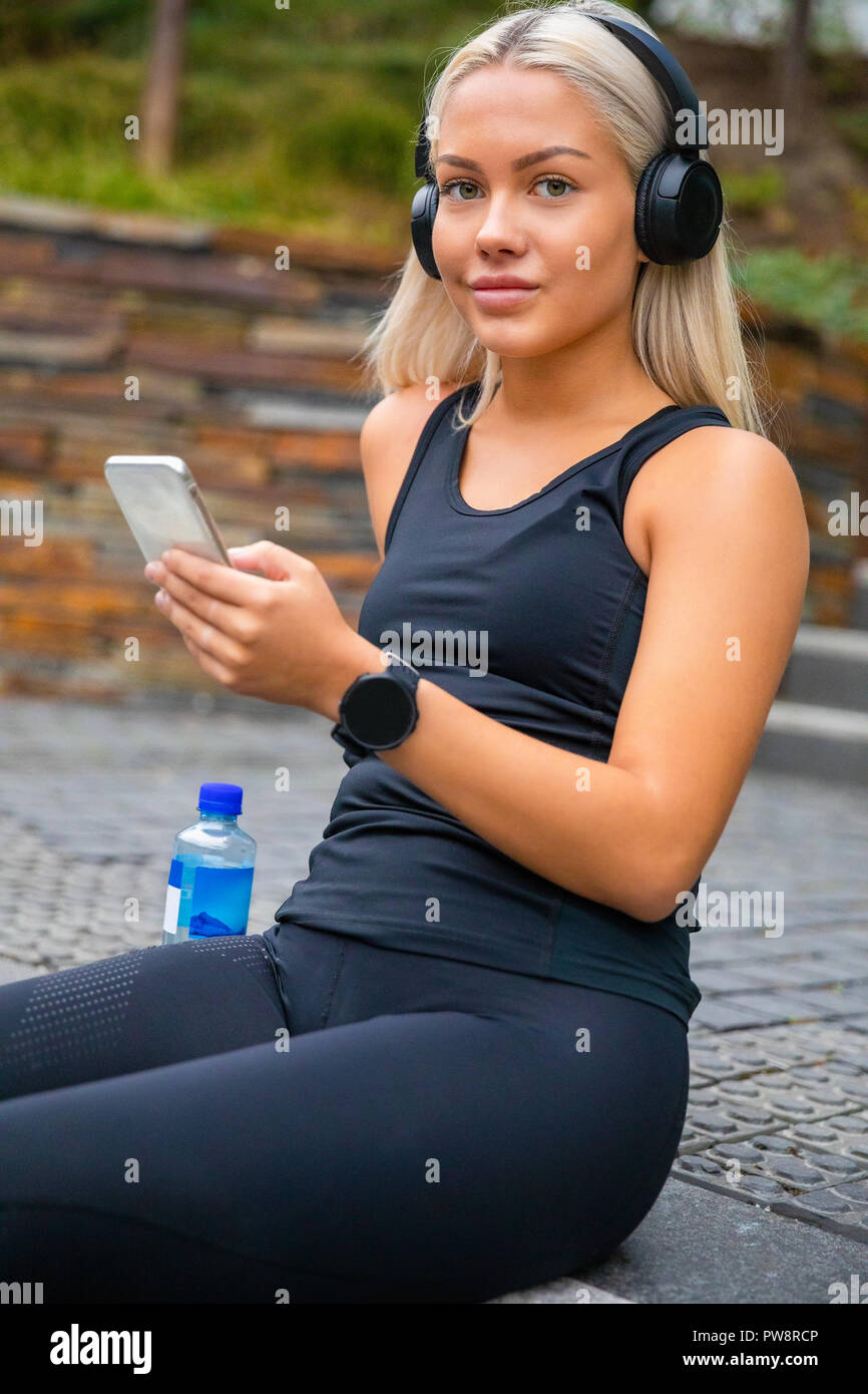 Sporty giovane donna ascolto di musica con cuffie e Smartphon Foto Stock