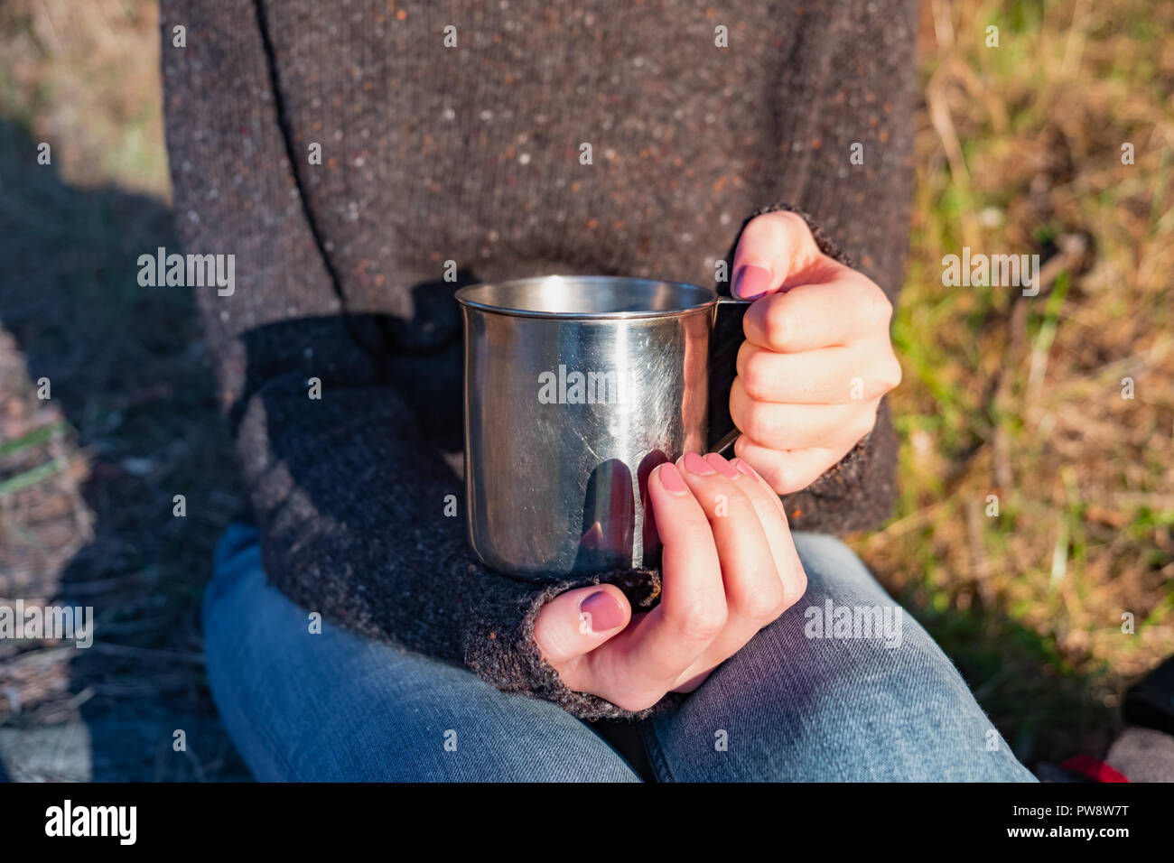 Grande tazza turistica in mani femminili. Immagine ravvicinata di una donna tenendo un bicchiere di metallo all'aperto Foto Stock