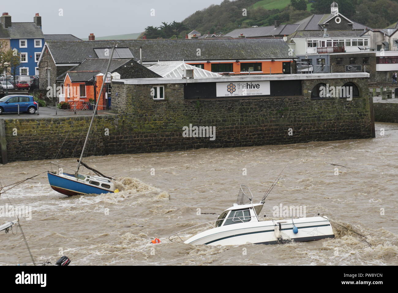 Aberaeron, UK. 13 ottobre 2018. Una scena di devastazione in Aberaeron Harbour sulla West Wales coast questo pomeriggio come heavy rain e alta venti di tempesta Callum continuare a causa della distruzione. Acqua di inondazione dal fiume Aeron alberi portanti e grossi rami in crash barche ormeggiate ci danno a molti e totalmente naufragio altri. Credito: Anthony Pugh/Alamy Live News Foto Stock