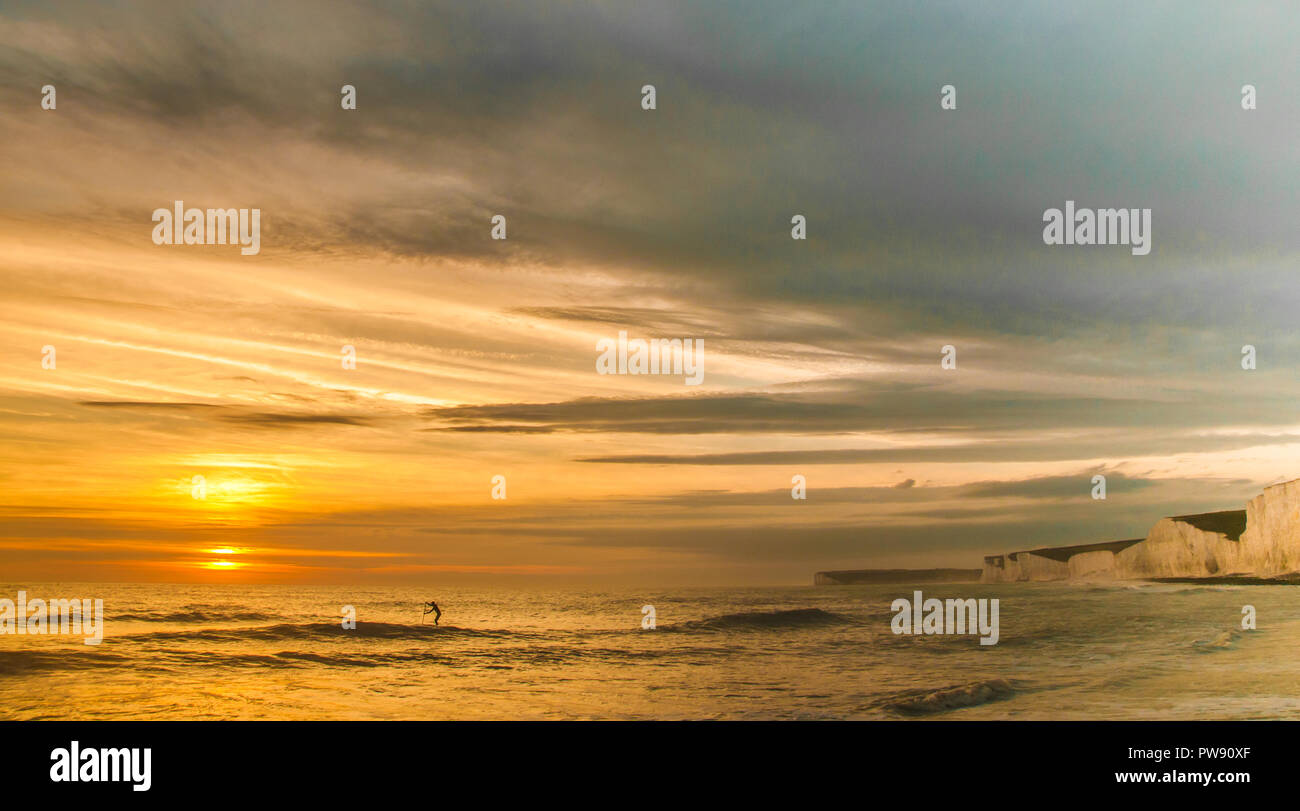 Birling Gap, Eastbourne, East Sussex, Regno Unito..13 ottobre 2018.. Una splendida serata balmy con vento caldo dal sud. Lone psdddle boarder... Foto Stock