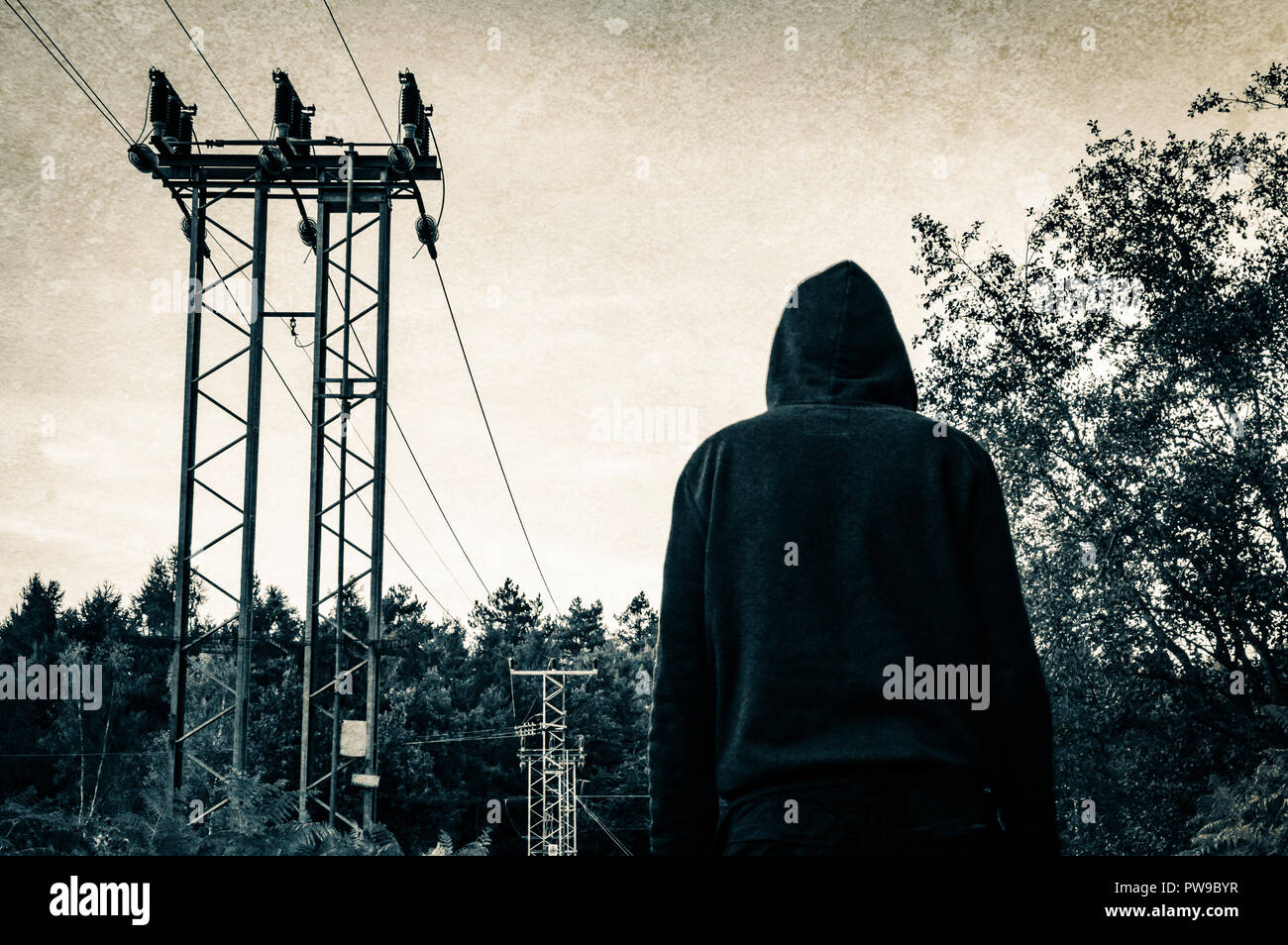 Cerca fino a una figura con cappuccio in una foresta accanto a tralicci con un vintage, grunge duo modifica del tono. Foto Stock