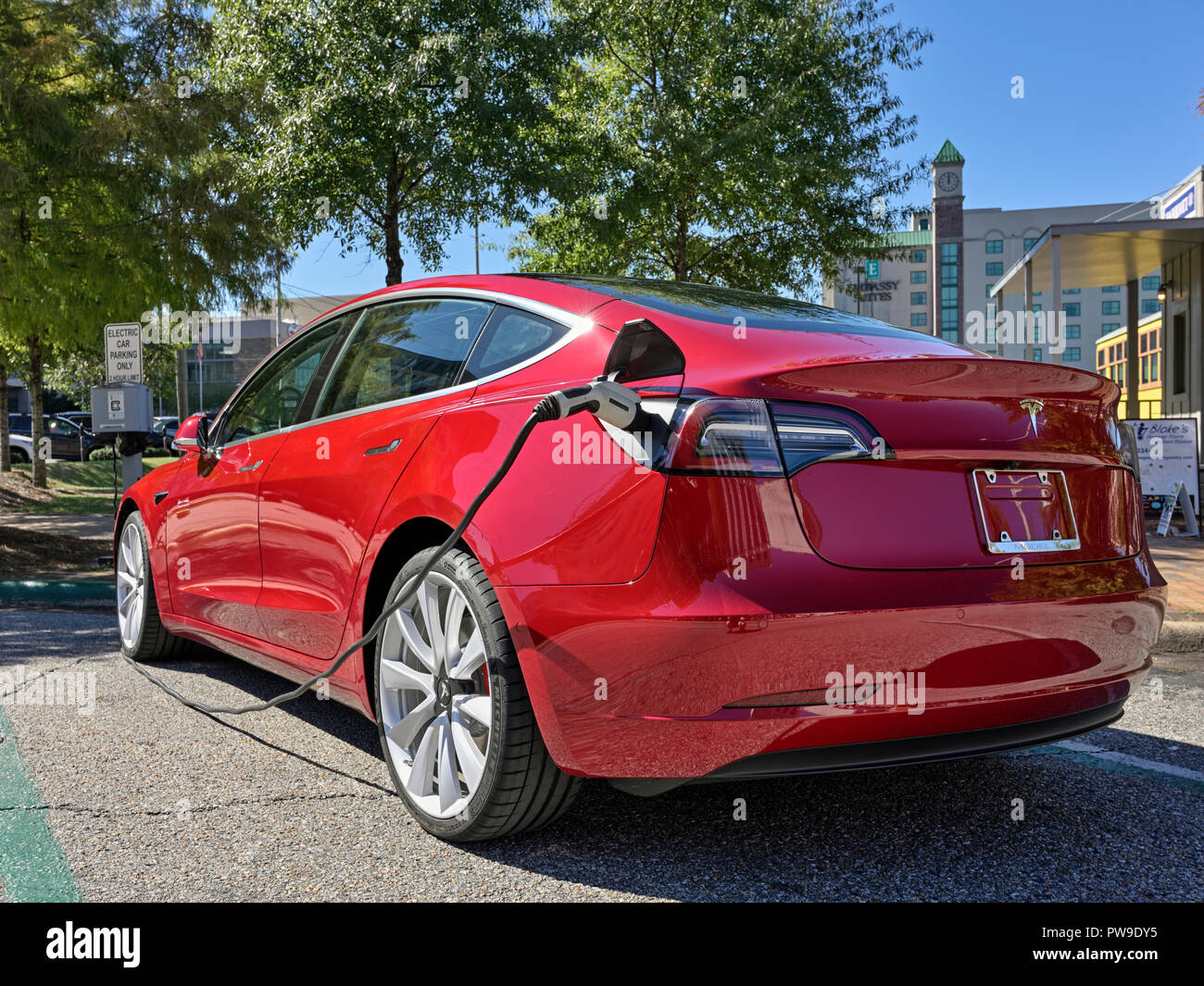 Rosso Modello Tesla tre (3), la sosta e la carica a un veicolo elettrico o auto elettrica stazione di ricarica su strada a Montgomery in Alabama, Stati Uniti d'America. Foto Stock