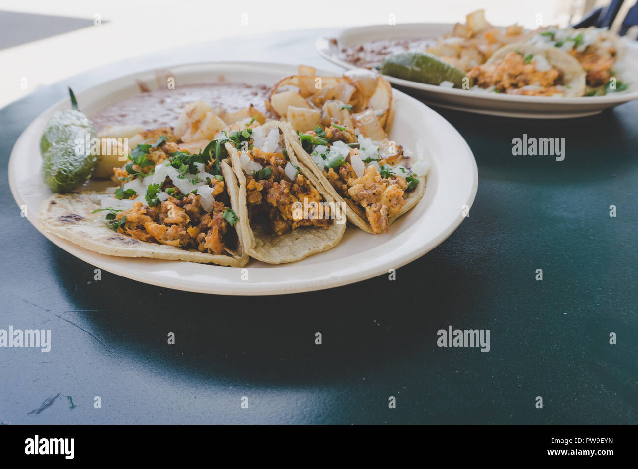 Un delizioso piatto di prima colazione tacos con refried fagioli a Los Angeles in un tavolo esterno. Foto Stock